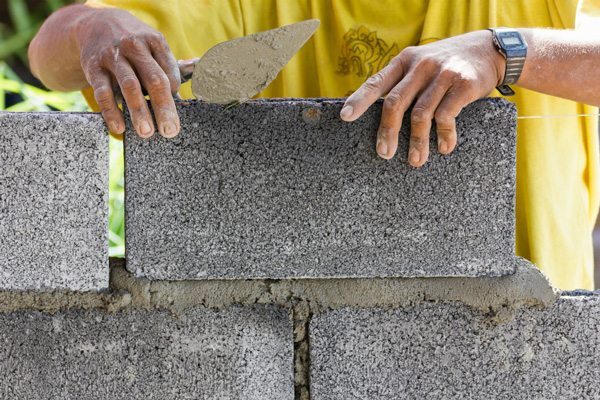 A man skillfully uses a trowel to construct a wall, showcasing his craftsmanship and dedication.