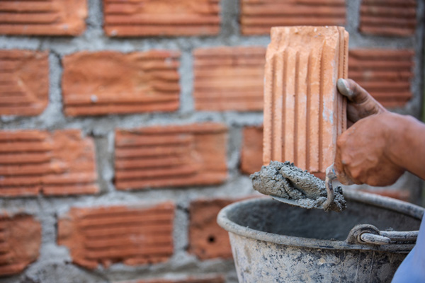 A person constructing a wall using a brick.