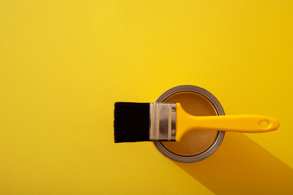 A paint brush on a yellow container.